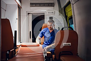 Positive paramedic sitting in the ambulance car and smiling at the camera with a toothy smile