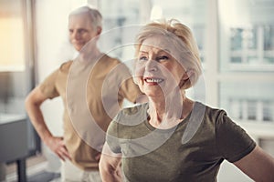 Positive pensioners doing physical exercises indoors