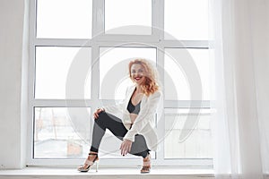 Positive person. Attractive redhead woman posing in the spacey room near the window