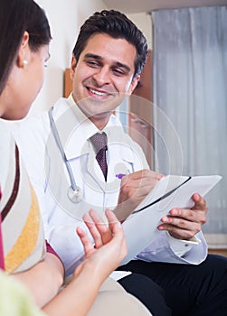 Positive physician consulting sick woman in domestic interior