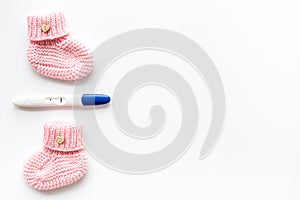 Positive pregnancy test. Baby girl concept with pink booties on white background top-down copy space