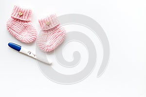 Positive pregnancy test. Baby girl concept with pink booties on white background top-down copy space