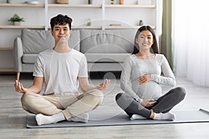 Positive pregnant asian couple doing yoga together