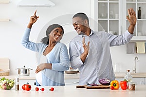 Positive pregnant black couple having fun while cooking