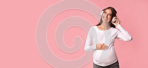 Positive Pregnant Lady Enjoying Music In Earphones, Pink Background, Panorama