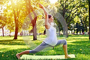 Positive pregnant woman meditating in yoga pose outdoors