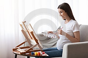 Positive Pregnant Woman Painting On Easel, Having Art Therapy Session At Home