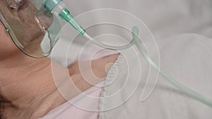 Positive pressure oxygen mask on a female patient lying in bed in a hospital room during an illness