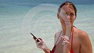 Positive pretty woman using smartphone on sea beach