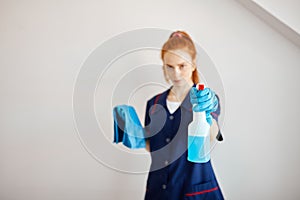 Housewife with red-haired ponytail holds dusting cloth and wiper.