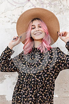 Positive pretty young woman with beautiful smile in fashionable black summer dress with floral print in straw hat. Attractive