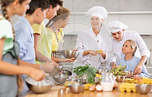 Positive professional chefs in white uniform conducting culinary masterclass for tweens