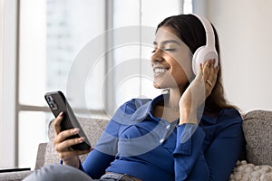 Positive relaxed young 20s Indian girl in big headphones