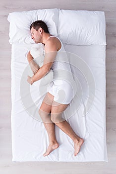 Positive and relaxed young man sleeping on bed