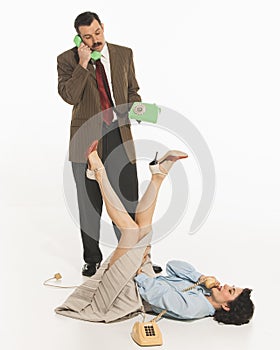 Positive and relaxed young woman lying on floor while man in suit standing and talking on phone. Diversity of emotions.