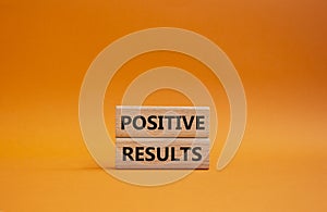 Positive results symbol. Concept words Positive results on wooden blocks. Beautiful orange background. Business and Positive