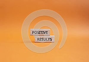 Positive results symbol. Concept words Positive results on wooden blocks. Beautiful orange background. Business and Positive