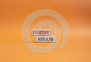 Positive results symbol. Concept words Positive results on wooden blocks. Beautiful orange background. Business and Positive