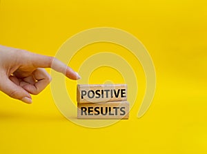 Positive results symbol. Concept words Positive results on wooden blocks. Beautiful yellow background. Businessman hand.