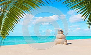 Positive sandy snowman in sunglasses at tropical ocean palm beach