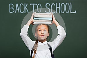 Positive schoolgirl holding stack of books