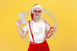 Positive self confident adult man in santa claus costume holding megaphone and looking at camera, ready to organize your holiday