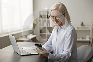 Positive senior business woman in glasses using digital gadgets