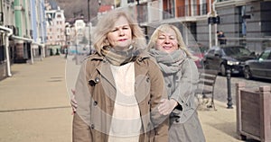 Positive senior caucasian woman running from background to waiting friend. Cheerful retirees meeting on sunny autumn day