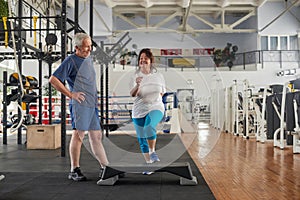 Positive senior couple exercising at gym.