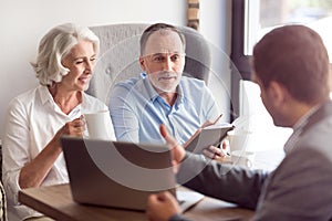 Positive senior couple talking with sales manager