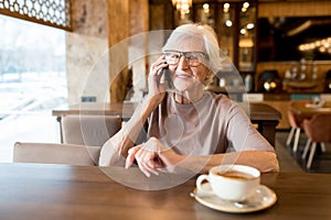 Positive senior entrepreneur talking by phone