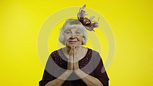 Positive senior old blond woman appealing to camera, keeping prayer gesture and asking help