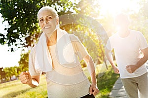 Positive senior woman jogging with her husband