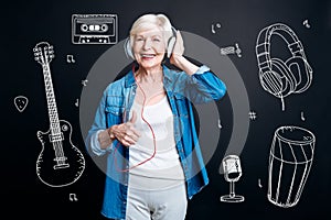 Positive senior woman putting her thumb up while listening to music