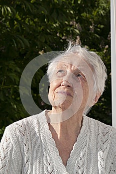 Positive senior woman watering decorative plants on balcony