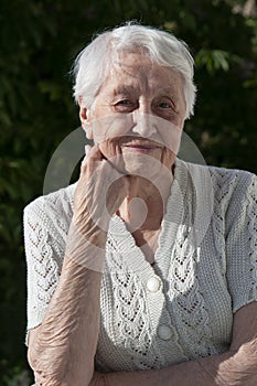 Positive senior woman watering decorative plants on balcony