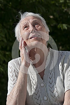 Positive senior woman watering decorative plants on balcony