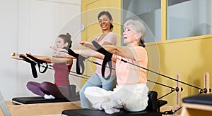 Senior woman doing stretching exercises on pilates reformer photo