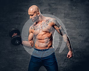 Positive shaved head shirtless male dressed in a jeans holds the