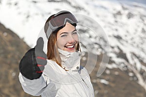 Positive skier woman gesturing thumb up in winter