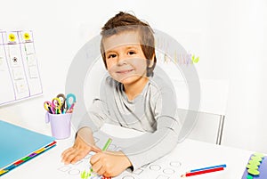 Positive small boy draws with pencil during ABA photo