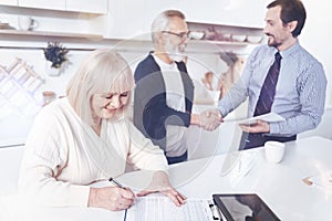 Positive smilign aged woman signing insurance contract
