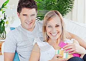 Positive smiling couple with woman opening present