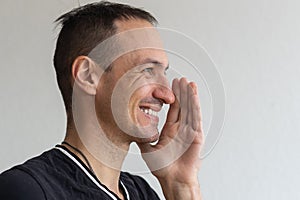 Positive smiling man with beard holding finger near lips showing shh gesture, keeping secrets preparing surprise. Indoor