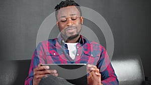 Positive smiling man watching social media in tablet and talking with himself.