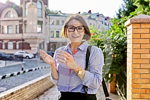 Positive smiling mature business woman wearing blue shirt glasses looking at camera