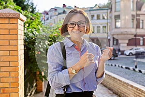 Positive smiling mature business woman wearing blue shirt glasses looking at camera