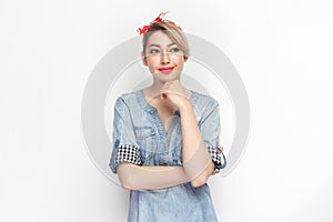 Positive smiling woman in blue denim shirt and red headband standing looking away, dreaming.