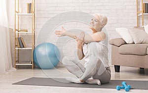 Positive sporty senior woman warming up at home