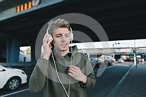 A positive student will listen to music on headphones while waiting for public transport at a bus stop under the bridge. Lifestyle